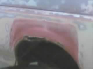 1989 Ford Bronco - Blurry close-up of a body panel being repaired, showing pink body filler feathered over sanded primer and bare metal around the top of a wh…