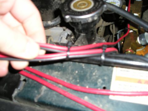 1996 Ford Bronco - Close-up view of red electrical wires in an engine bay, with a hand adjusting them.
