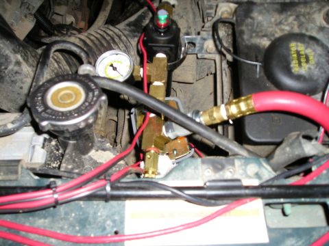 1996 Ford Bronco - Close-up of engine bay components, including a pressure gauge and air line fittings.