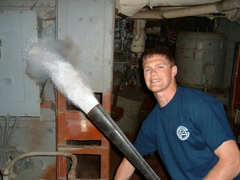 1989 Ford Bronco - A man operates a water nozzle in what appears to be an industrial or ship interior.