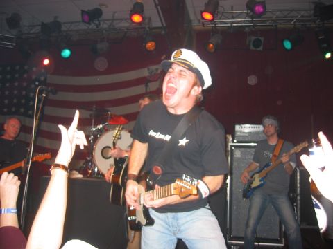 1989 Ford Bronco - A band performs live on stage in front of an American flag, with the lead singer in a captain's hat.
