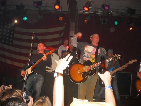 1989 Ford Bronco - Musicians perform live on stage with instruments and an American flag backdrop.