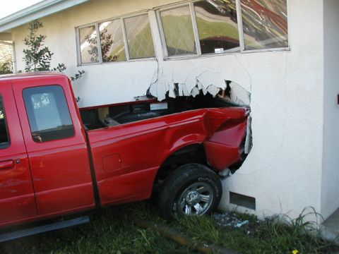 2000 Ford Ranger - A red pickup truck has crashed through the wall of a building, leaving a gaping hole.