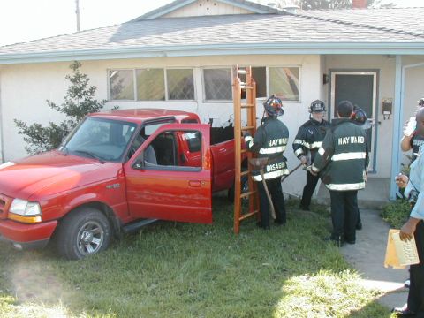 2000 Ford Ranger - A red 2000 Ford Ranger has driven into the side of a house, with firefighters on the scene.