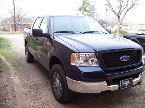 2005 Ford F-150 - This dark blue 2005 Ford F-150 pickup truck is shown from a 3/4 front angle, a prominent Ford grille and a "Sewell 95" dealer plate.