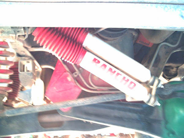 Rancho shock absorber with red boot installed on truck suspension, viewed from underneath