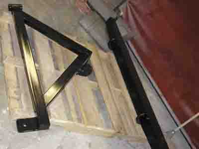 1988 Ford Bronco - A black metal bracket with a pivot mechanism is shown, resting on a wooden pallet.
