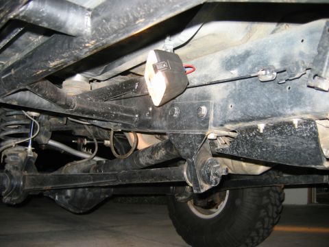 1985 Ford Bronco - Undercarriage view of a vehicle, focusing on suspension components and an aftermarket rock light.