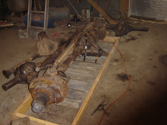 Several rusty vehicle axles on a wooden pallet