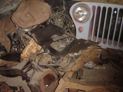 1992 Ford Bronco - A Jeep CJ-6 grille and headlight assembly is visible amidst a collection of rusty vehicle parts.