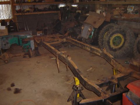 1992 Ford Bronco - A collection of vehicle parts and a rusted frame are stored in a cluttered garage.