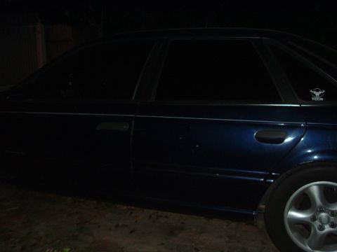 1993 Ford Taurus - Side profile of a dark blue sedan, tinted windows and a distinctive bull emblem on the rear passenger window.