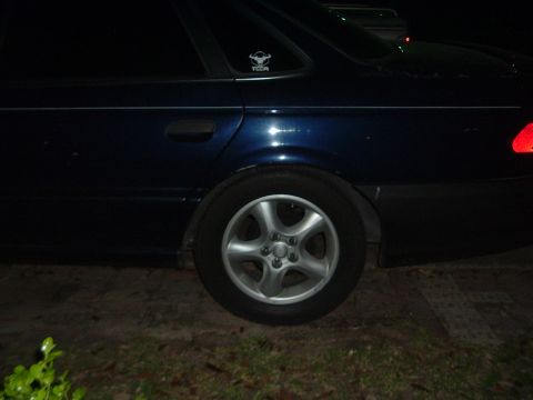 1993 Ford Taurus - Rear quarter panel and wheel of a dark blue 1993 Ford Taurus sedan.