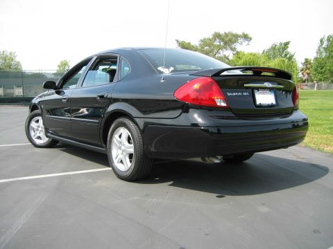 2002 Ford Taurus - Black Ford Taurus SE sedan photographed from the rear three-quarter showing trunk badge and spoiler.