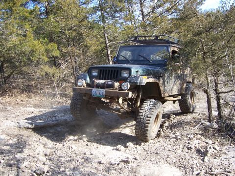 1999 Jeep TJ - This Jeep Wrangler YJ is navigating a rough, off-road path through a wooded area.