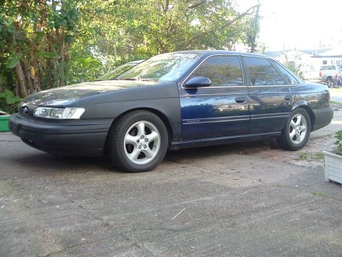 1993 Ford Taurus - This Ford Taurus sedan has a primer-colored front fender and hood, contrasting with the rest of the blue body.