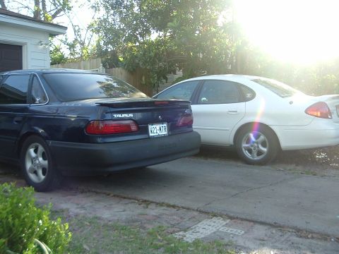 1993 Ford Taurus - Two Ford Taurus sedans are parked side-by-side in a driveway.