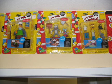 1994 Ford Crown Victoria - The Simpsons action figures are displayed in their packaging on a shelf.