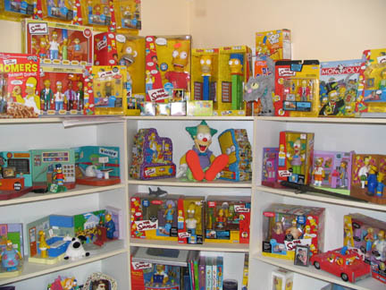 1994 Ford Crown Victoria - A collection of The Simpsons themed toys and merchandise is displayed on shelves.