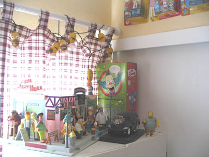1994 Ford Crown Victoria - A shelf displays a diorama of The Simpsons characters and buildings, along with a toy car and action figures.
