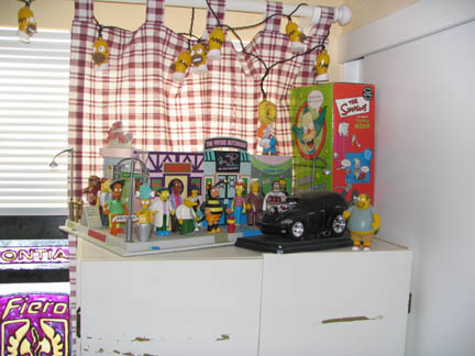 1994 Ford Crown Victoria - A black hot rod with an exposed engine sits in front of a Simpsons-themed display.