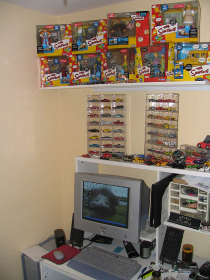 1994 Ford Crown Victoria - A collection of The Simpsons action figures and numerous toy cars are displayed on shelves.