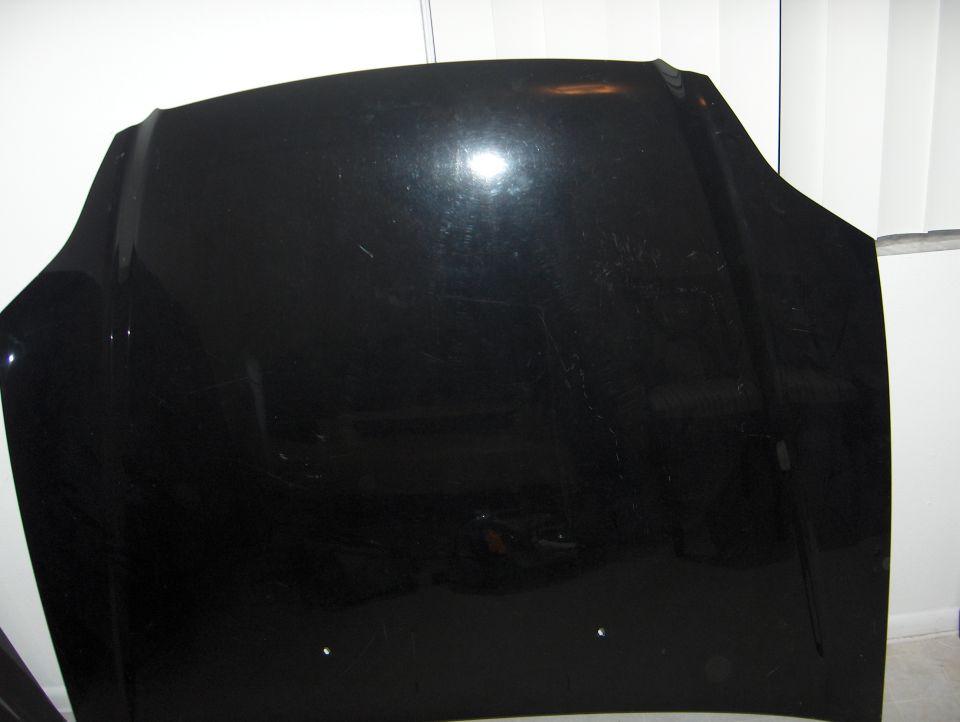 Black car hood with scratches, viewed from the front