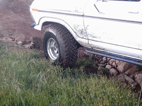 1978 Ford Bronco - A white 1978 Ford Bronco is shown off-roading over rocks and dirt.