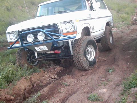 1978 Ford Bronco - This modified SUV is navigating a challenging dirt path with steep inclines and ruts.