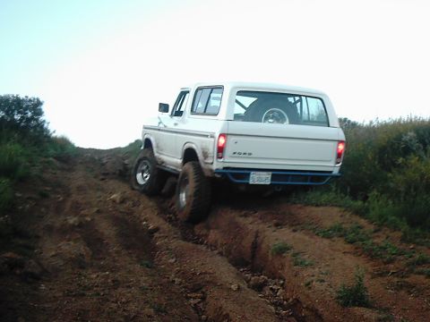 1978 Ford Bronco - A white 1978 Ford Bronco navigates a challenging off-road incline, demonstrating its capability.