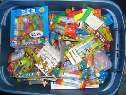 1994 Ford Crown Victoria - A blue plastic tub overflows with a collection of Pez dispensers and candy, various characters and themed packaging.