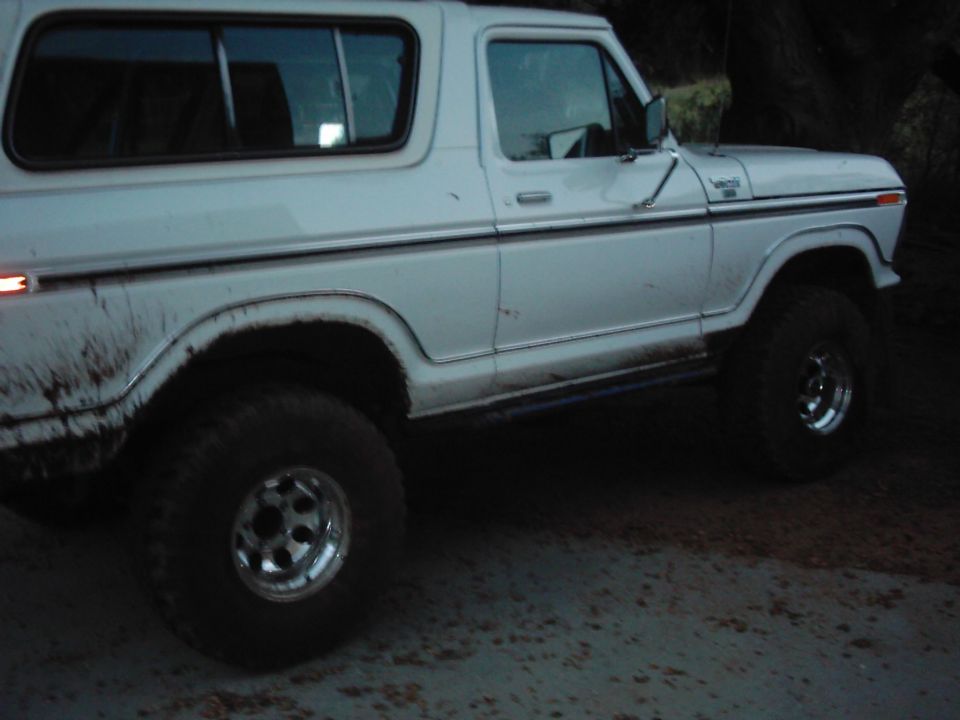 White 1978 Ford Bronco with aftermarket wheels and tires, side view