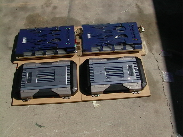 Four Kenwood car amplifiers on MDF boards, two blue flame-cut, two silver