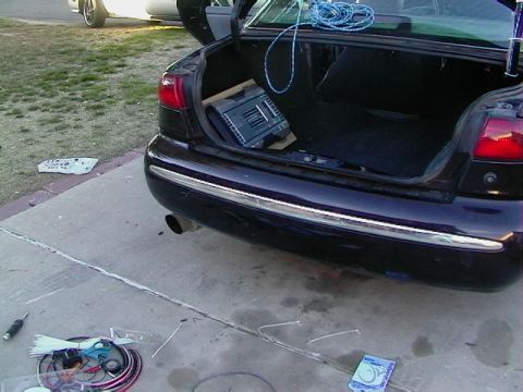 1995 Ford Contour - Rear view of a dark purple sedan with its trunk lid open, a finned car-audio amplifier board propped inside the trunk and blue rope coiled…