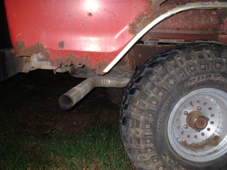 1978 Ford Bronco - Close-up of a vehicle's rear wheel well, showing rust and an exhaust pipe.