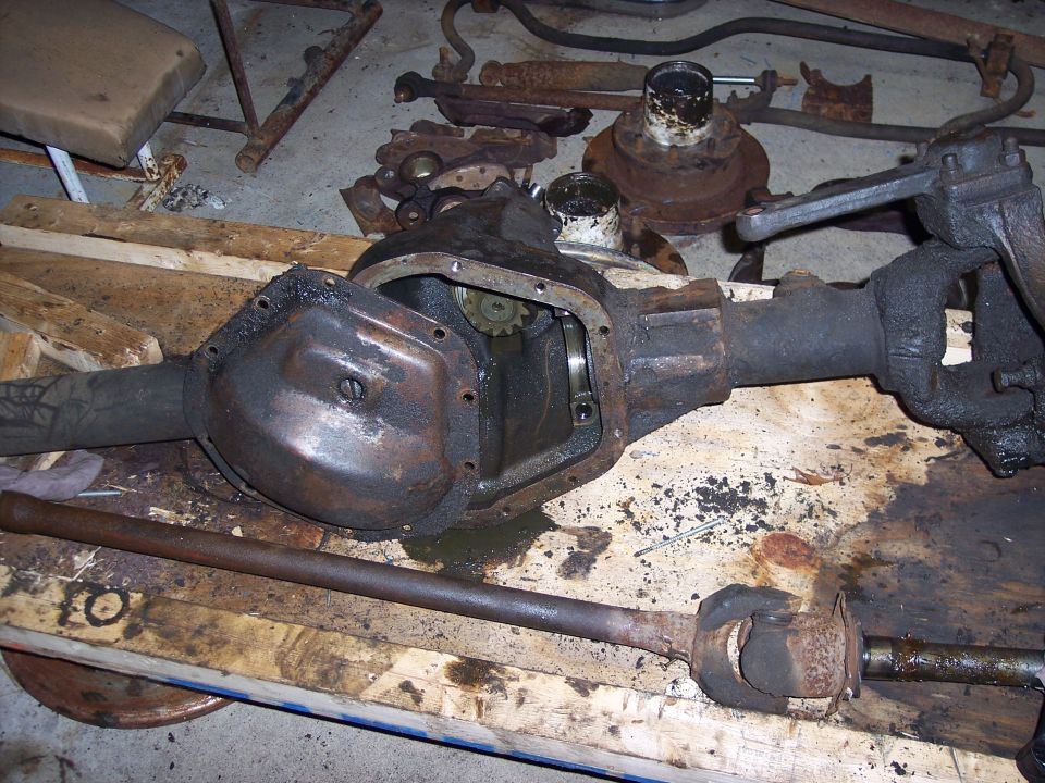 Dana 60 axle assembly with differential cover removed, showing gears. Other suspension parts are scattered around