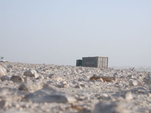 1988 Ford Bronco - Two shipping containers sit in a desolate, rocky area under a hazy sky.