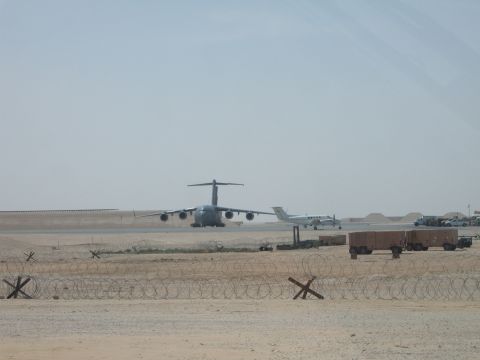 1988 Ford Bronco - Two aircraft are visible on a dusty airfield, with barbed wire fencing in the foreground.