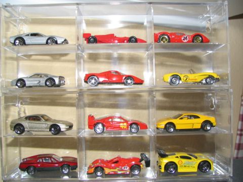 1994 Ford Crown Victoria - A collection of various toy sports cars are neatly arranged in a clear plastic display case, different models and colors.