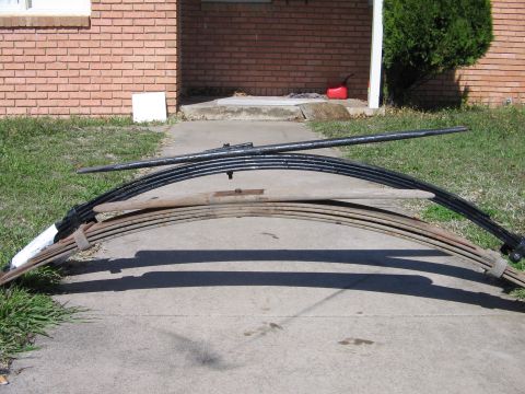 1978 Ford Bronco - Leaf springs are shown laid out on a driveway, likely for a vehicle lift installation.