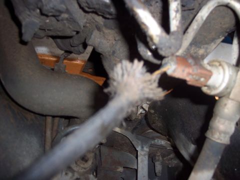 1988 Ford Bronco - A close-up view of damaged wiring and various hoses within the engine compartment.