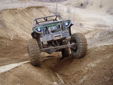 1992 Ford Bronco - An off-road vehicle navigates a steep dirt incline, its heavy-duty tires and suspension system.