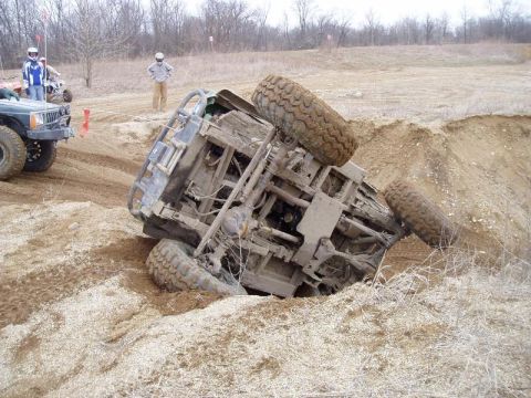 1992 Ford Bronco - An off-road vehicle has overturned in a dirt ditch, while another vehicle appears to be assisting.