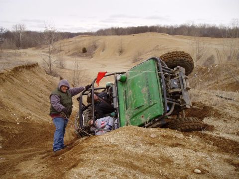 1992 Ford Bronco - Off-road buggy tipped over on a sandy hill with a person observing the scene.