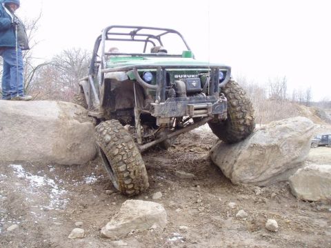 1992 Ford Bronco - This modified Suzuki is navigating a challenging rocky terrain, with another vehicle visible in the background.