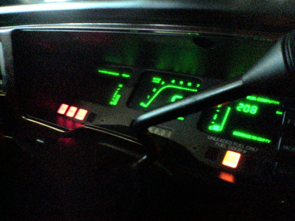 Green digital dashboard cluster lit at night showing 208 on trip computer