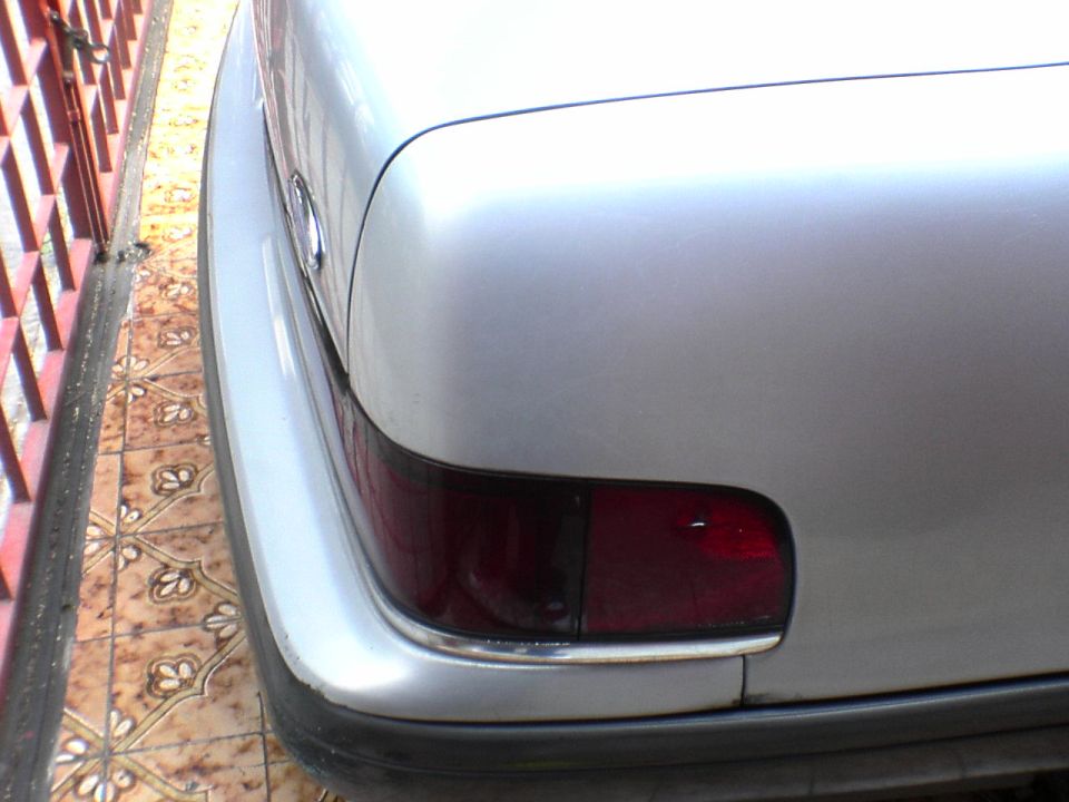 Rear corner of silver sedan with red taillight and chrome trim