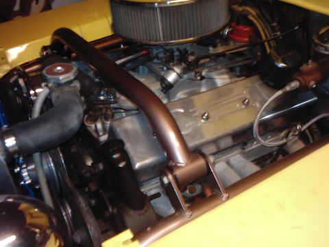 1978 Ford Bronco - Close-up view of a vehicle's engine bay, a copper-colored roll cage and chrome air filter.