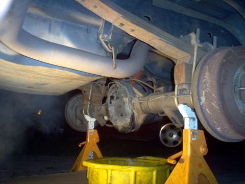 1988 Ford Bronco - The underside of a vehicle is shown, focusing on the rear axle and suspension components supported by jack stands.