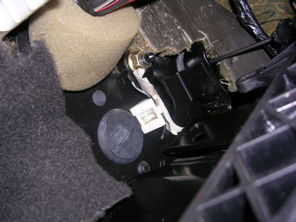 Close-up of a car's interior mechanical linkage and foam insulation